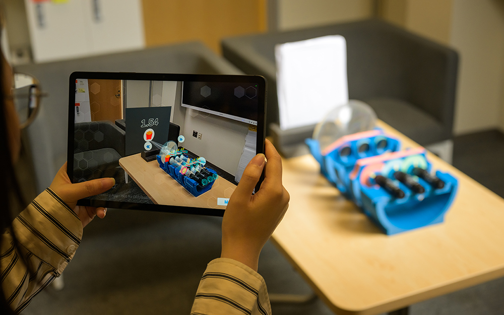 Hands holding a tablet taking a picture of a prototype design.
