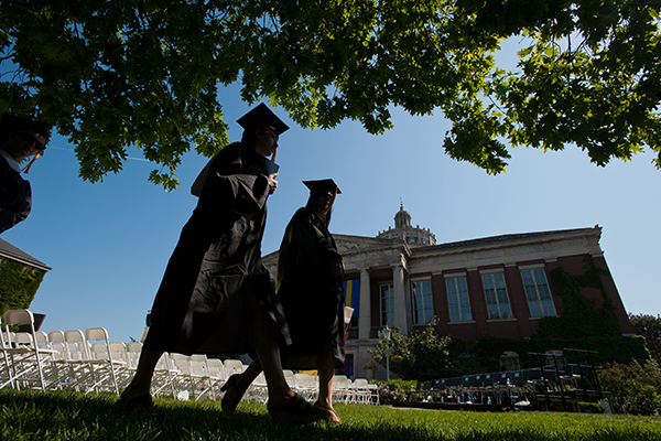 Two students in caps and gowns crossing the quad.