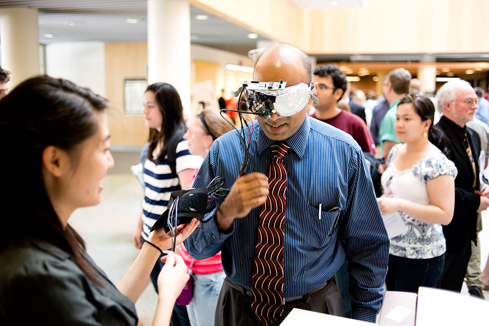 A student explaining their design to a person wearing an optical device.