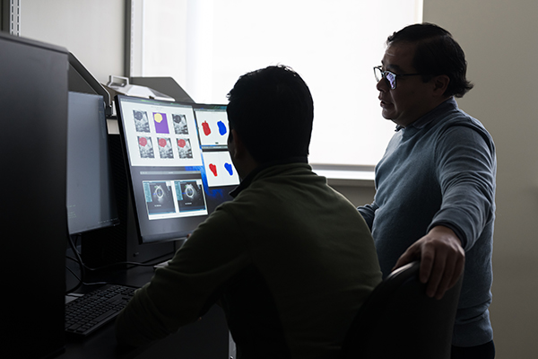 Researchers reviewing data on multiple computer screens.