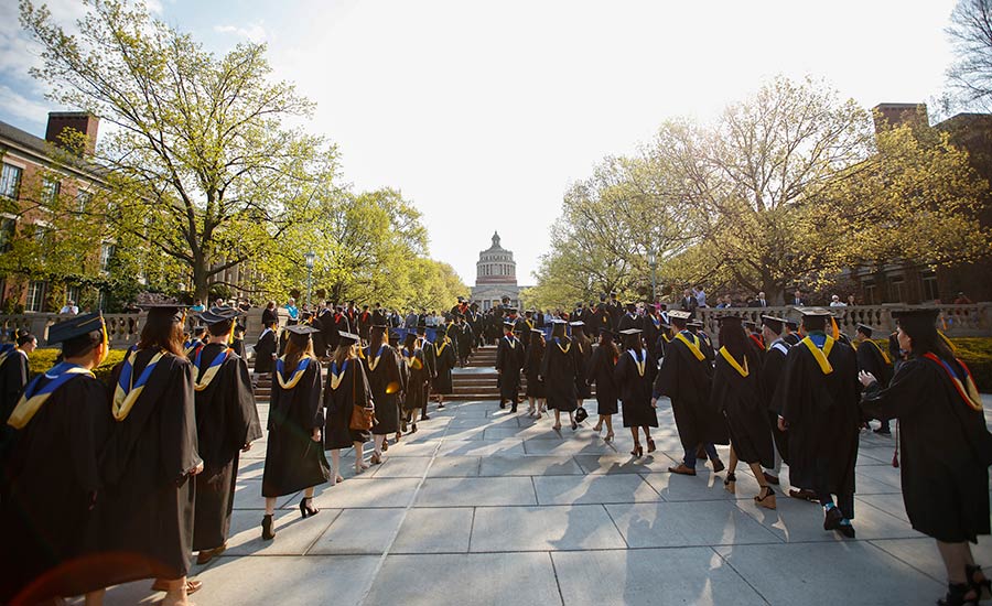 Students walking at commencement to receive her diploma.