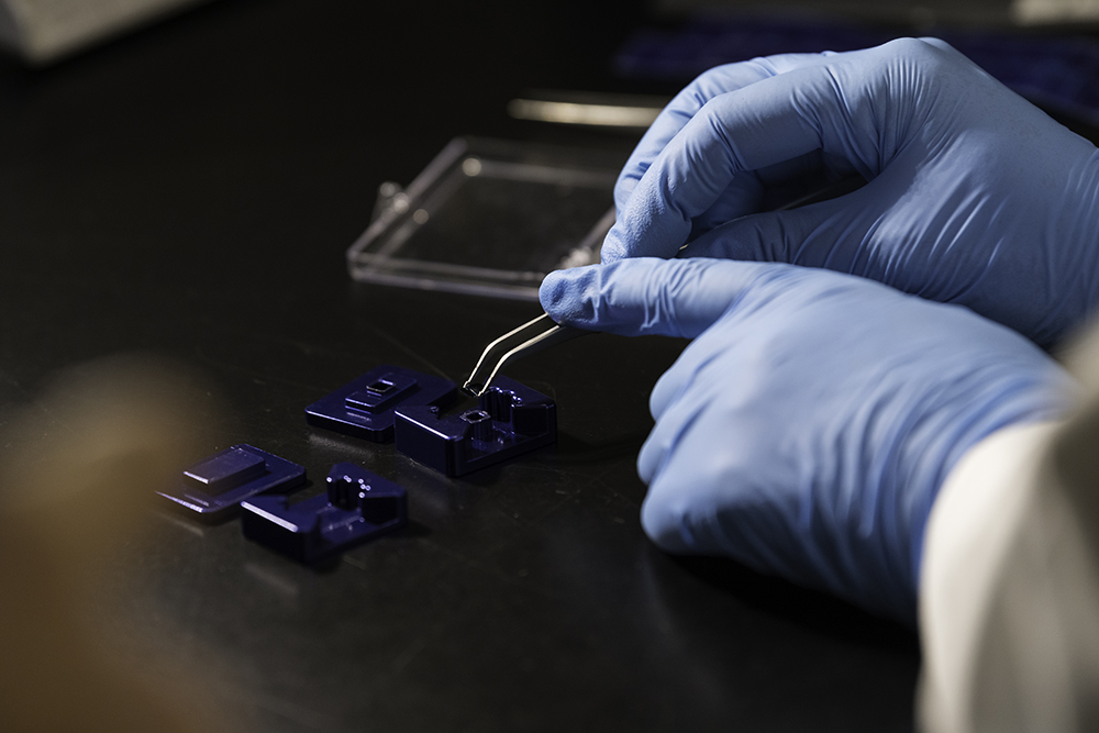 Gloved hands using tweezers to apply a chip.