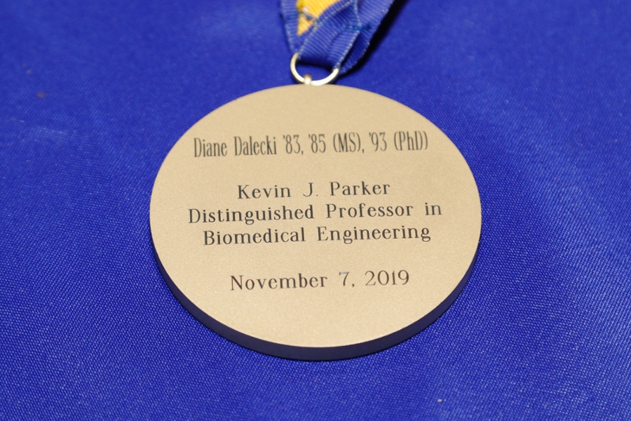 A gold medal on a blue ribbon engraved with Professor Dalecki's credentials, distinguished title and the date of November 7, 2019.