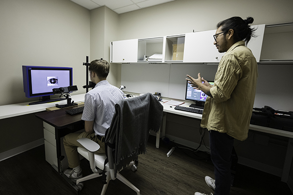 A lab assistant is pictured with a study subject in the lab.