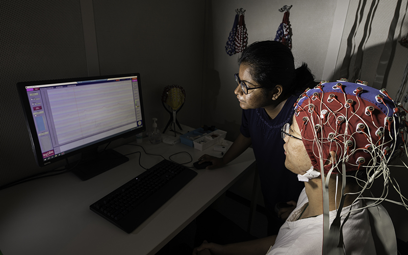 A student viewing data from an electroencephalography cap that a fellow student is wearing.