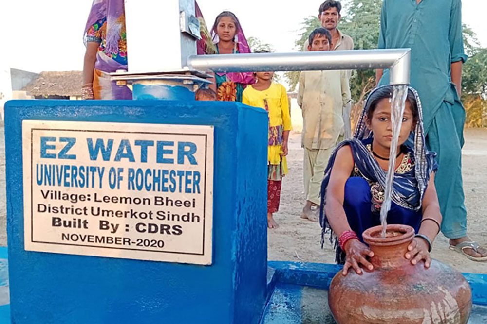 A woman filling a bucket with water from a community well.