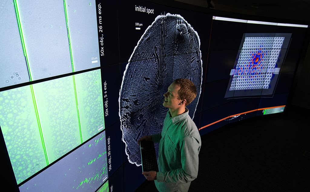 A person looking at data on a large screen in a darkened room.