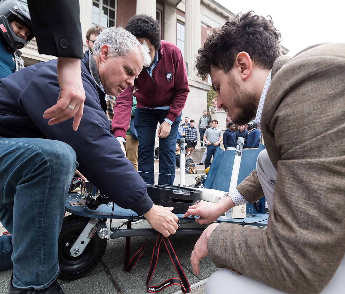 A group of people gathered around the prototype from a project.