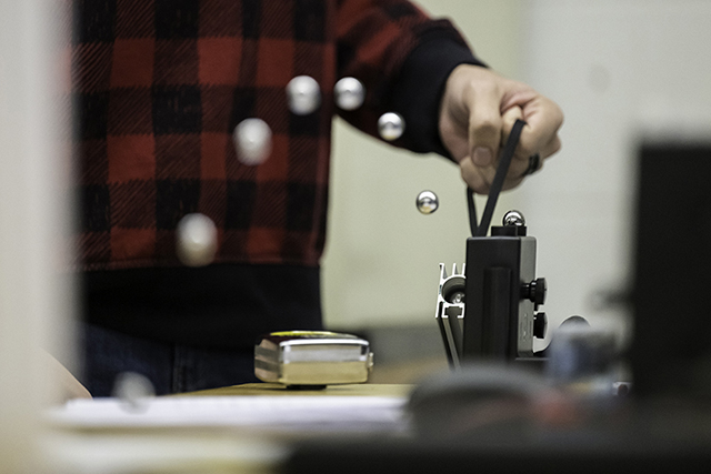 A student shooting metal balls with a spring-loaded launcher.