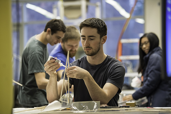 A student constructs a balsa wood efficient structure for a mechanical engineering class.