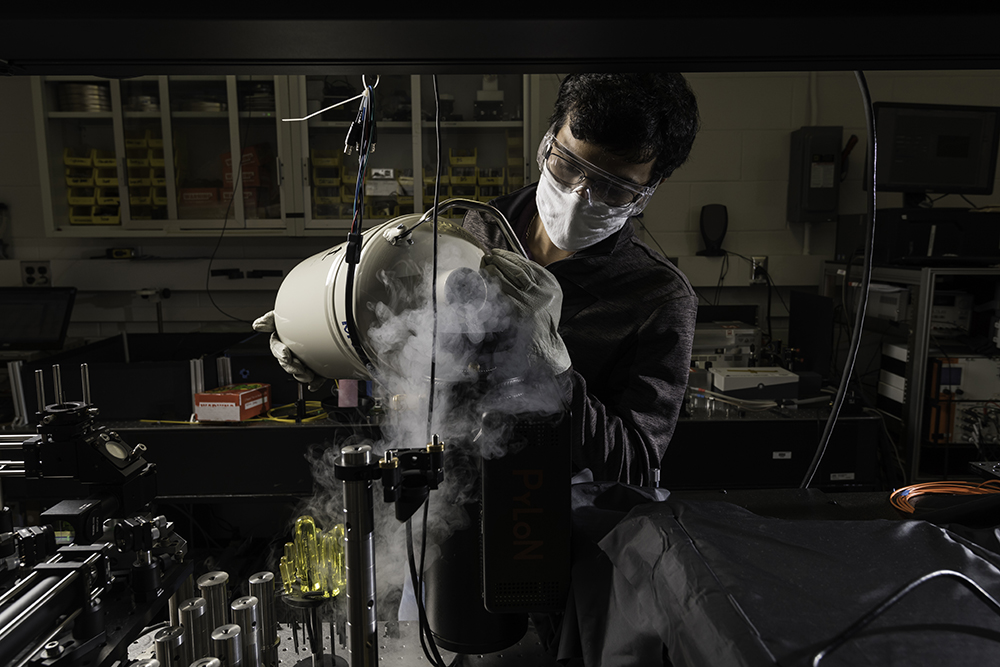 A student is pictured with equipment in a quantum lab.