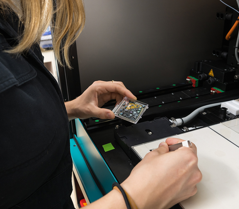 A student loads photonic sensor chips into a printer to be functionalized with capture molecules.
