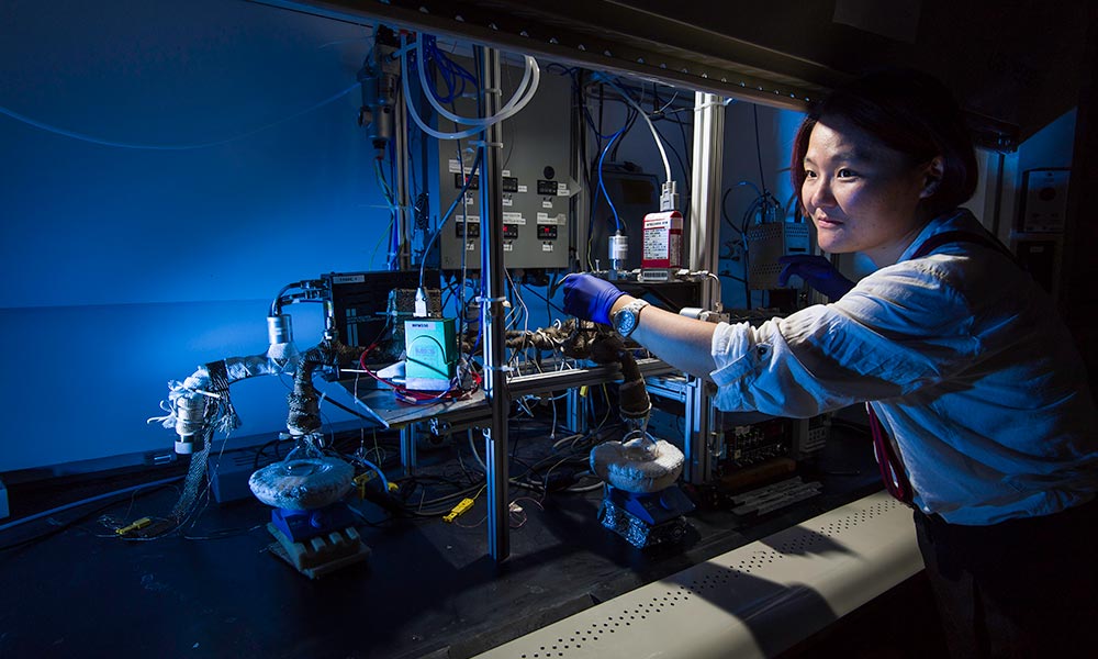 PhD student works with a initiated chemical vapor deposition reactor to synthesize solid electrolytes for 3-D microbatteries.