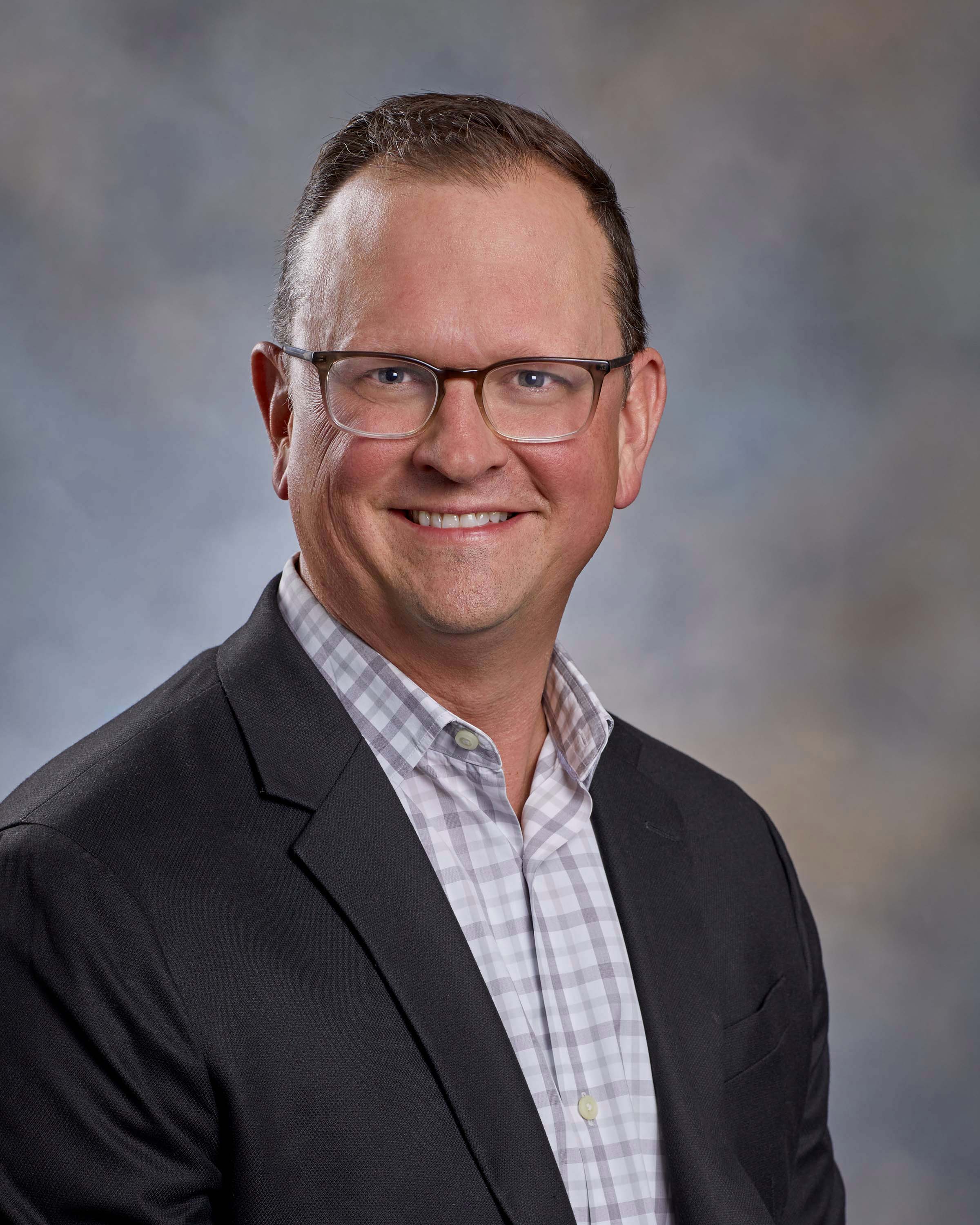 Headshot of a man in a suit with glasses