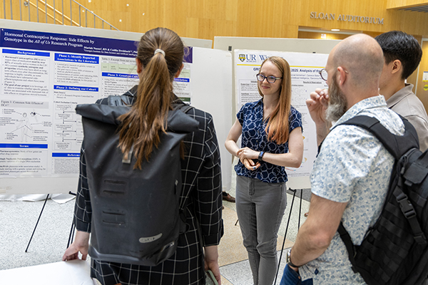 A student speaks about their poster to attendees.