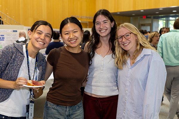 Four students in a group smiling at the camera.