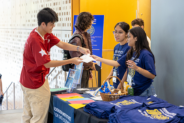 Students behind a table handing out t-shirts.