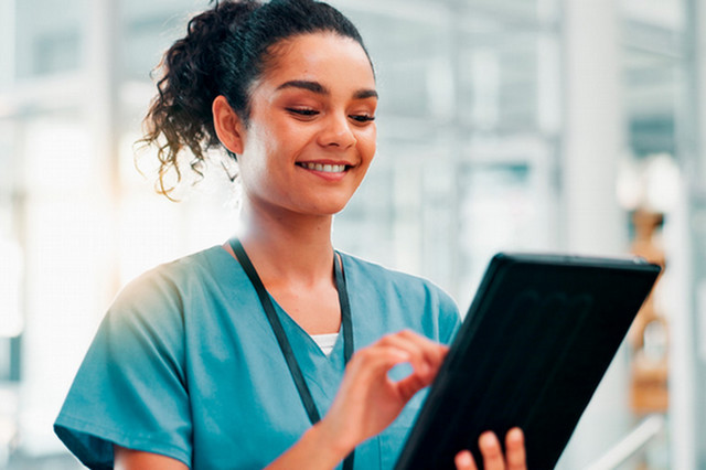 Woman in scrubs holding a tablet.