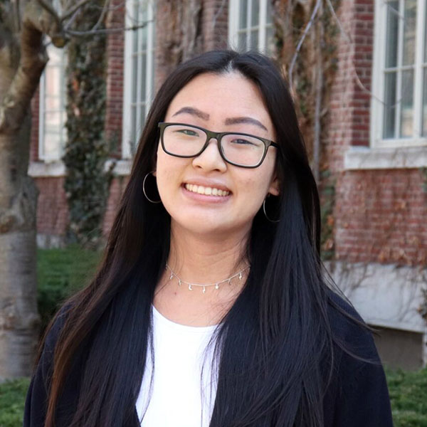Sarah Lee stands in front of a brick building on Eastman Quad.