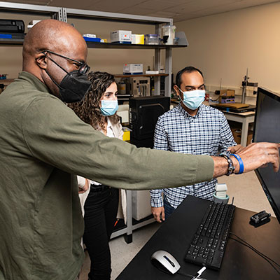 Professor of Electrical and Computer Engineering, Biomedical Engineering, and Imaging Sciences Marvin Doyley (L) is pictured in his lab with PhD students Irteza (Enan) Kabir (R) and Reem Mislati, in the Computer Studies building.