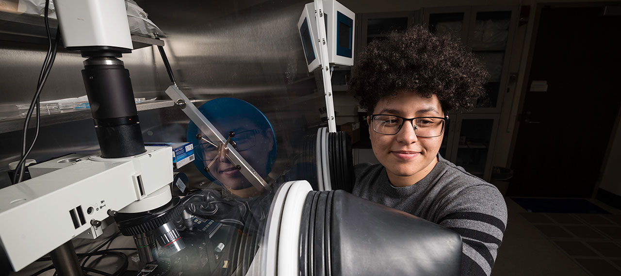 A student in a lab with an electromagnetic generator.