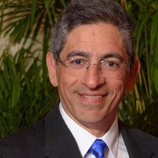 Man smiling at camera wearing dark suit and blue tie
