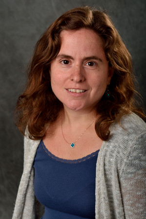 Woman smiling at camera wearing dark shirt and light sweater