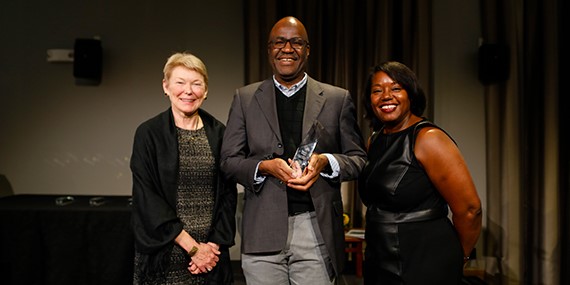 three people hold award and looking at camera