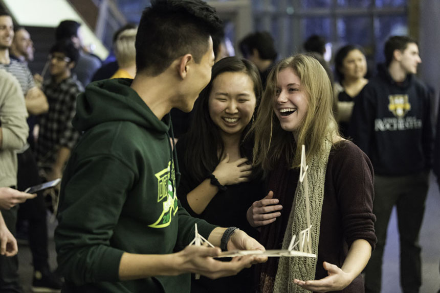 Students laugh and console each while holding the fragments of their structure