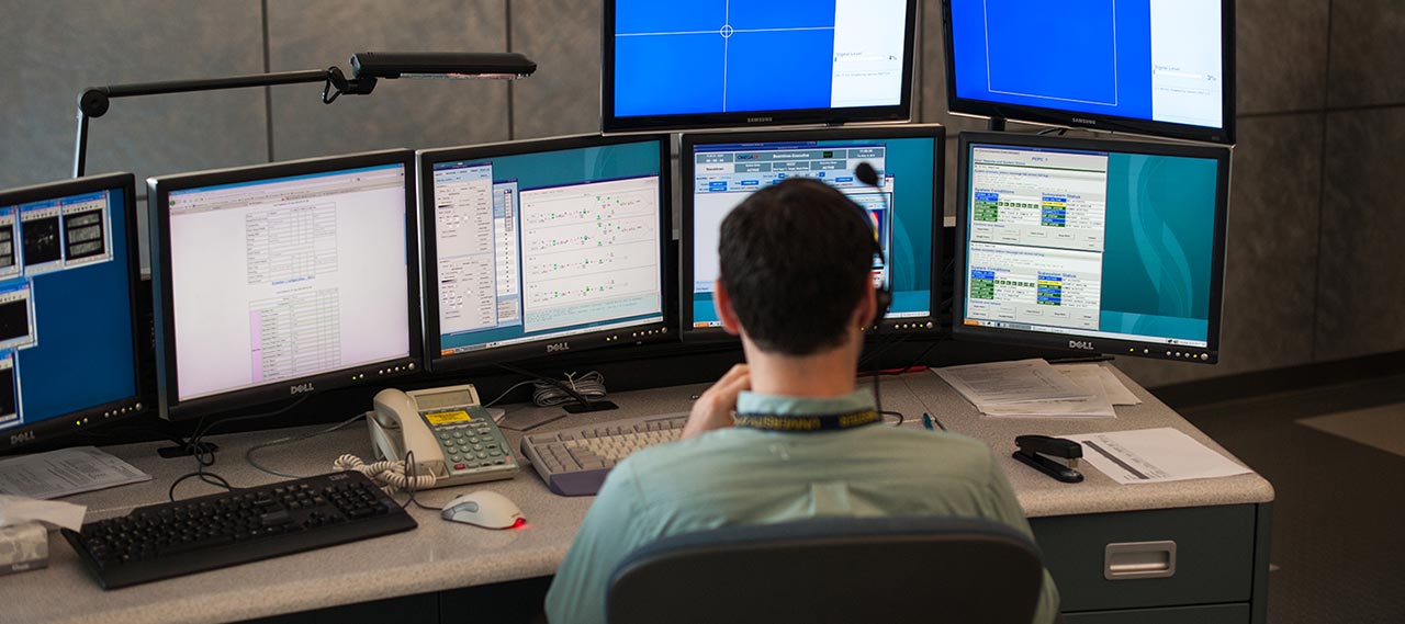 A student in front of multiple computer screens.