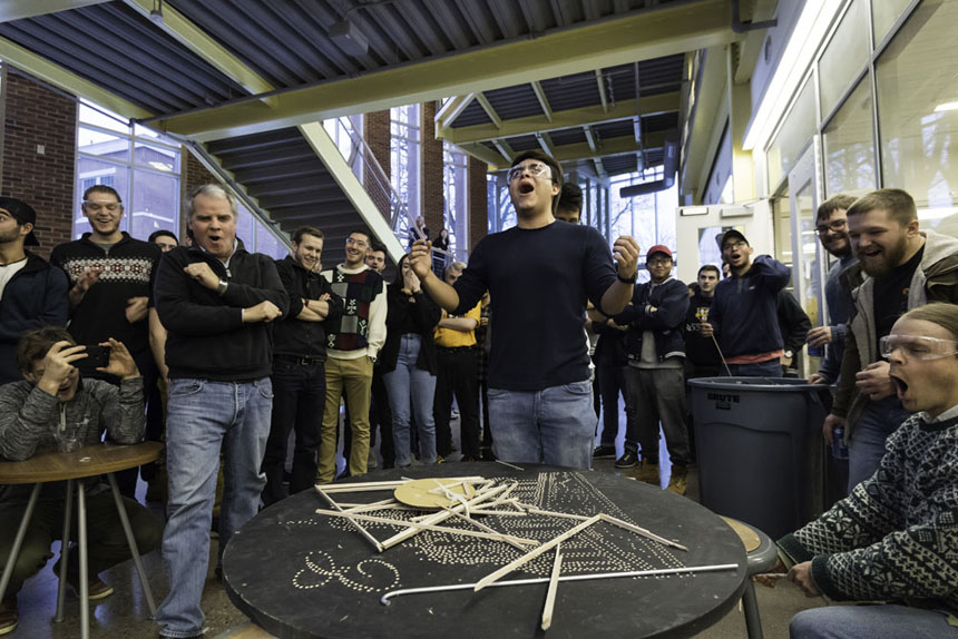 A student throws his hands in the air as his team's structure snaps to pieces