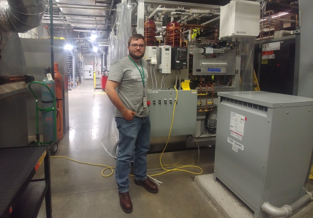 Peter Miklavcic posing next to the device he helped create at ORNL