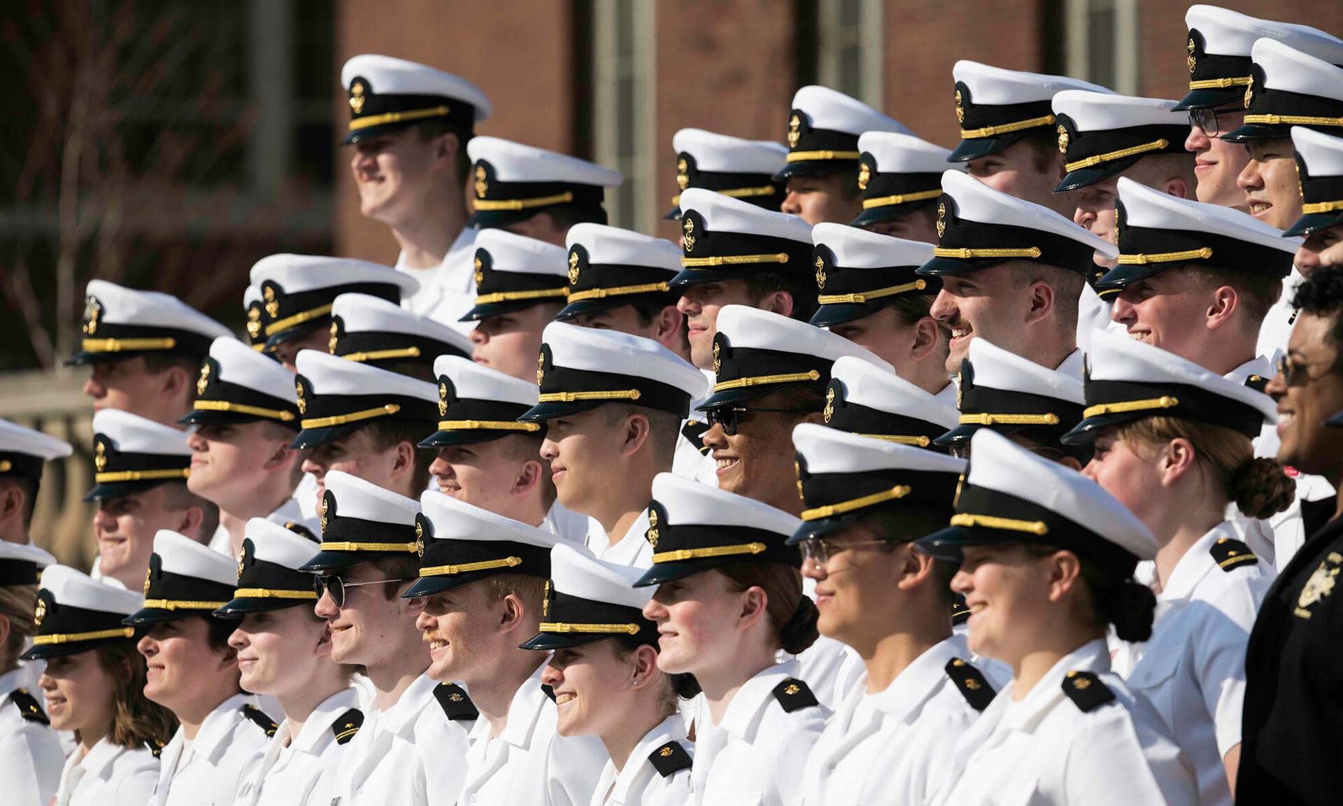 Side view of a large group of URochester NROTC members having a group photo taken on Eastman Quad.