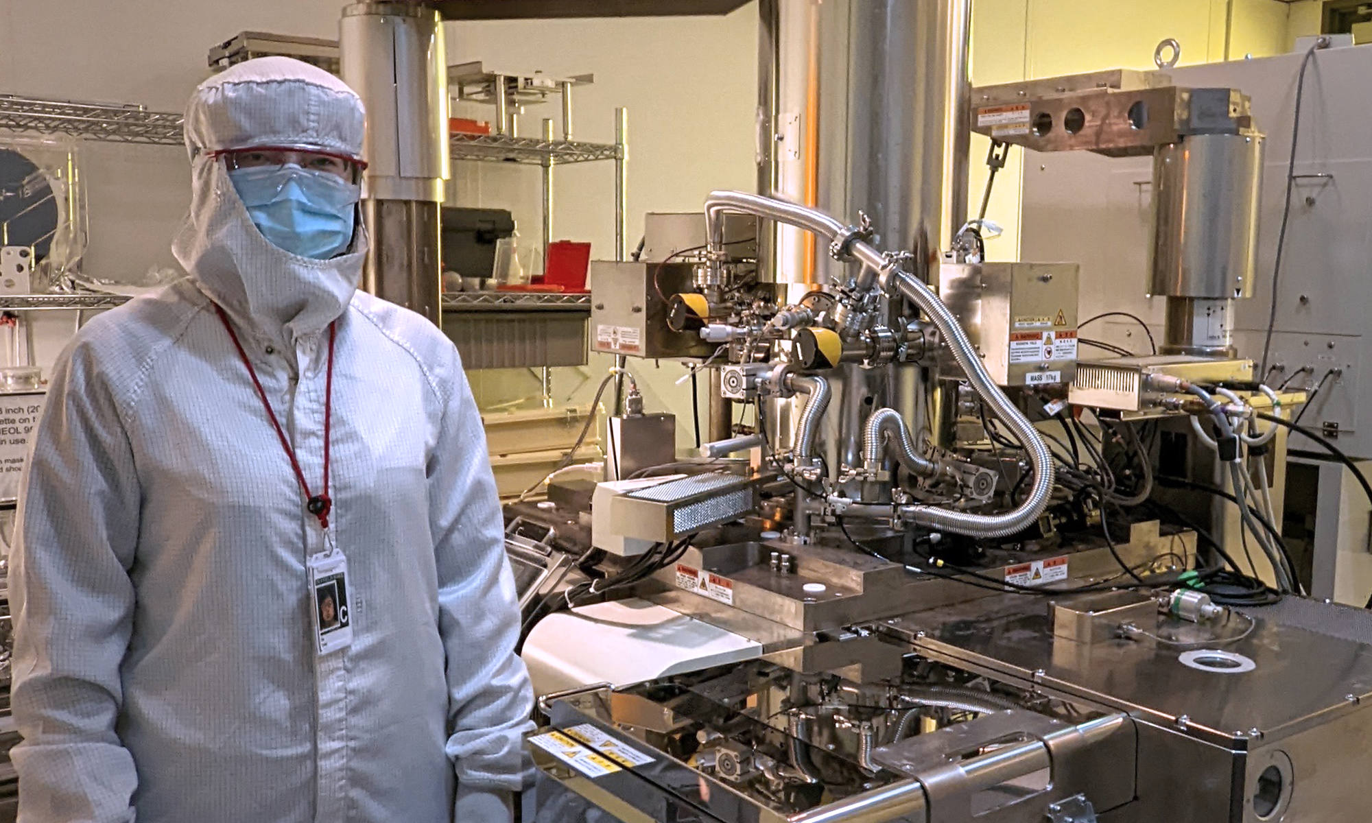 Yang He ’20 (PhD), an electrical and computer engineering postdoctoral scholar, stands beside an electron beam lithography system used to develop new microcomb technology.