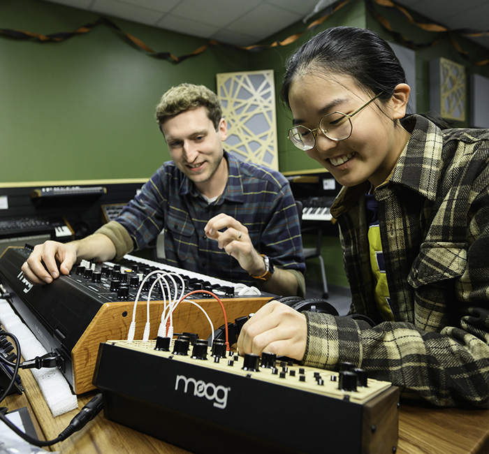 A professor and a student working with sound equipment in a studio.